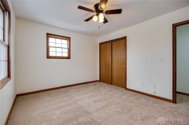 unfurnished bedroom featuring light colored carpet, ceiling fan, and a closet