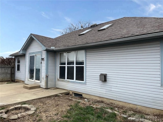 back of house with a patio, a shingled roof, and fence