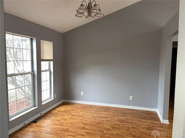 spare room with light hardwood / wood-style floors and a chandelier