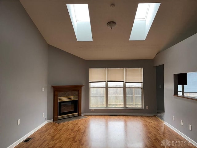 unfurnished living room featuring lofted ceiling with skylight and light wood-type flooring