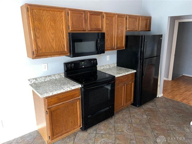 kitchen with black appliances, brown cabinetry, and light countertops