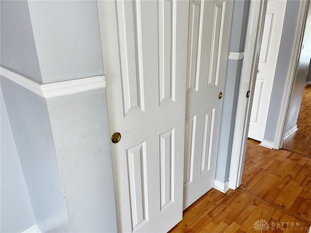 corridor with baseboards and wood finished floors