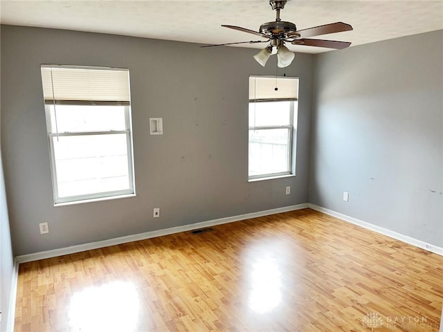 spare room featuring light wood-type flooring, baseboards, visible vents, and a ceiling fan