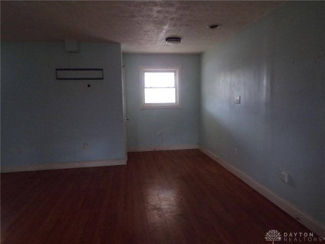 empty room featuring dark wood-type flooring and a textured ceiling