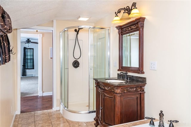 bathroom featuring tile patterned floors, ceiling fan, a textured ceiling, a shower with shower door, and vanity