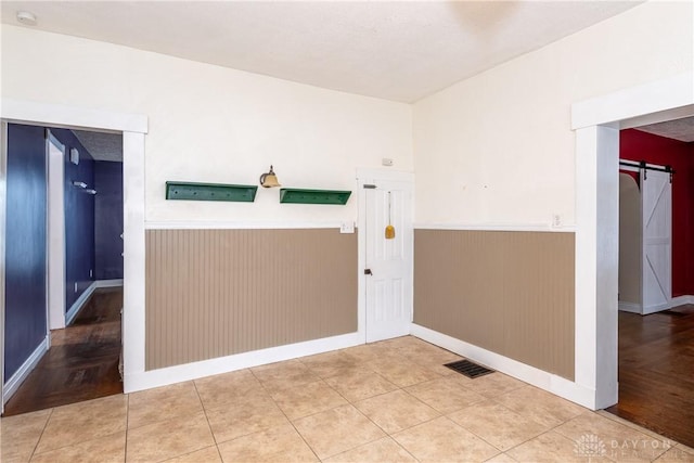 interior space featuring wood walls, tile patterned floors, and a barn door