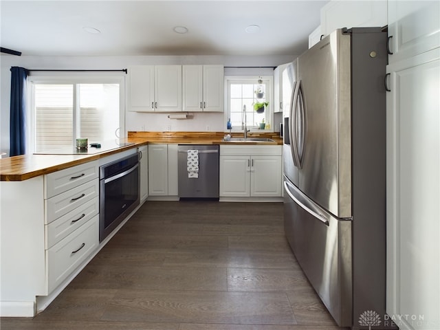 kitchen with wooden counters, white cabinetry, stainless steel appliances, sink, and dark hardwood / wood-style floors