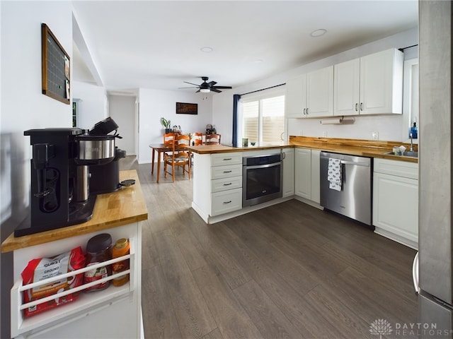 kitchen with kitchen peninsula, white cabinetry, butcher block countertops, and stainless steel appliances