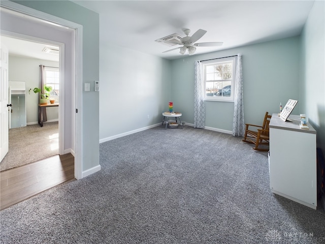 miscellaneous room featuring ceiling fan, a healthy amount of sunlight, and dark carpet