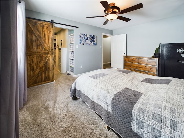 bedroom featuring ceiling fan, a barn door, and carpet flooring