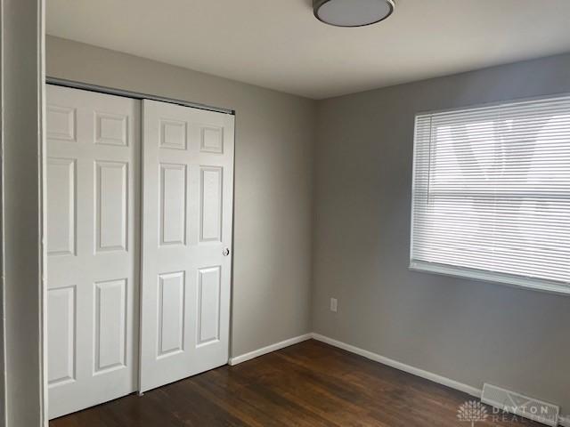 unfurnished bedroom with a closet and dark wood-type flooring