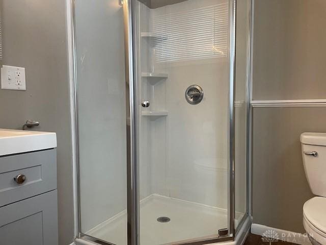 bathroom with toilet, vanity, and an enclosed shower