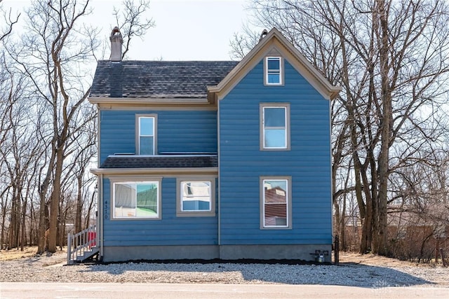 view of front of home featuring a chimney and a shingled roof