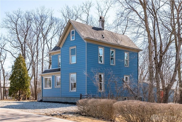 exterior space featuring a chimney and a shingled roof