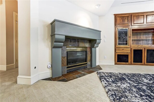 details with a tile fireplace and carpet flooring