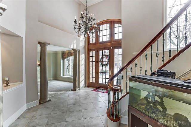 tiled entryway with a towering ceiling, a healthy amount of sunlight, and ornate columns