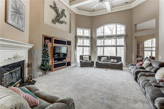 living room with coffered ceiling, ornamental molding, a high ceiling, and carpet flooring