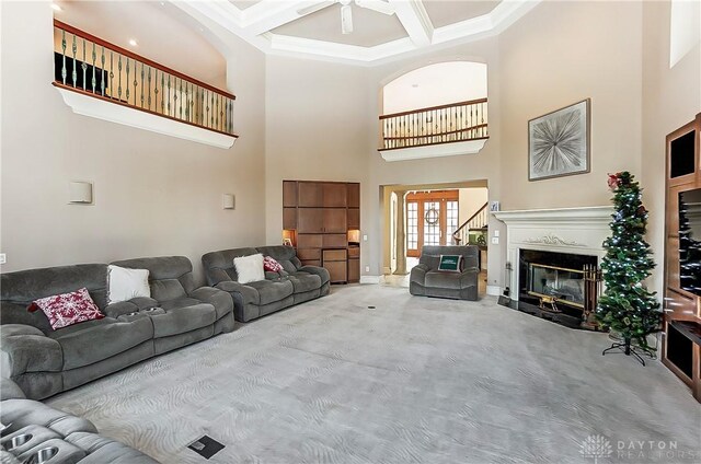 living room featuring a high ceiling, coffered ceiling, ornamental molding, light carpet, and beamed ceiling