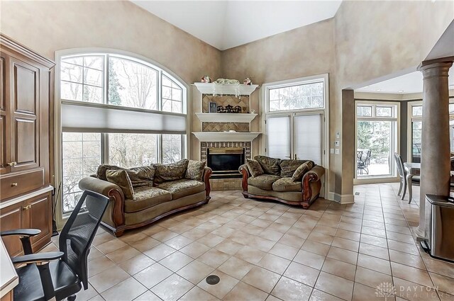 tiled living room featuring ornate columns, a towering ceiling, and a wealth of natural light