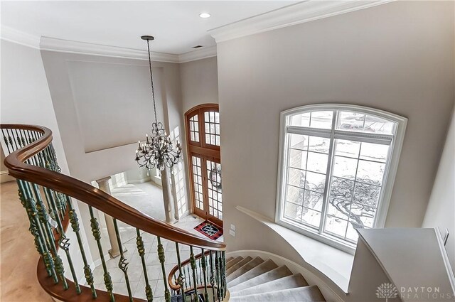 stairway with an inviting chandelier and ornamental molding