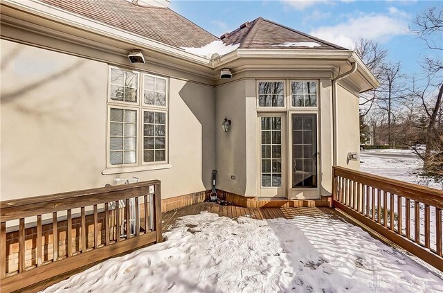 snow covered property entrance with a deck