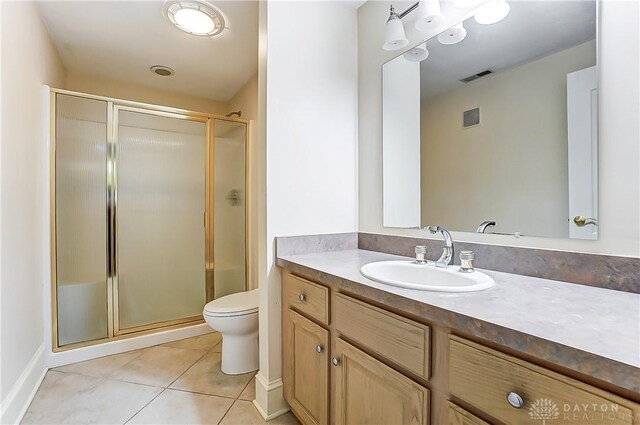 bathroom featuring a shower with door, vanity, tile patterned floors, and toilet