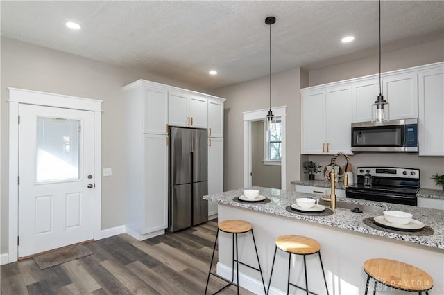 kitchen with decorative light fixtures, light stone countertops, white cabinetry, and stainless steel appliances