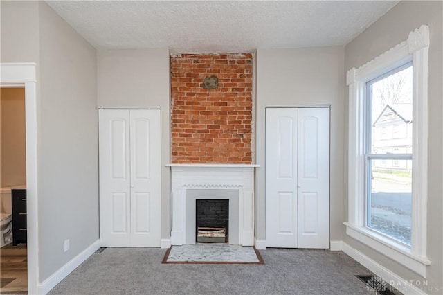 unfurnished living room featuring carpet floors, a textured ceiling, and a fireplace