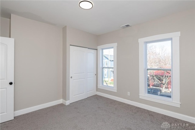 unfurnished bedroom with a closet and light carpet