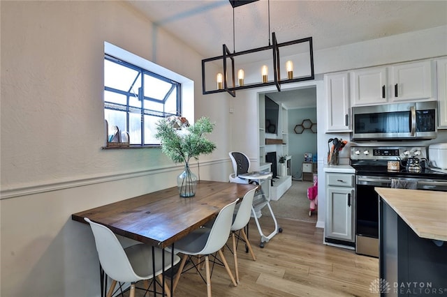 kitchen featuring wooden counters, white cabinets, pendant lighting, and stainless steel appliances