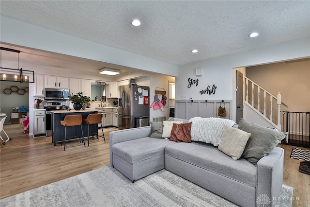 living room featuring light hardwood / wood-style floors, a textured ceiling, and a chandelier