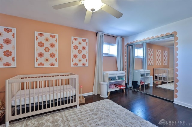 bedroom with ceiling fan, dark hardwood / wood-style flooring, and a crib