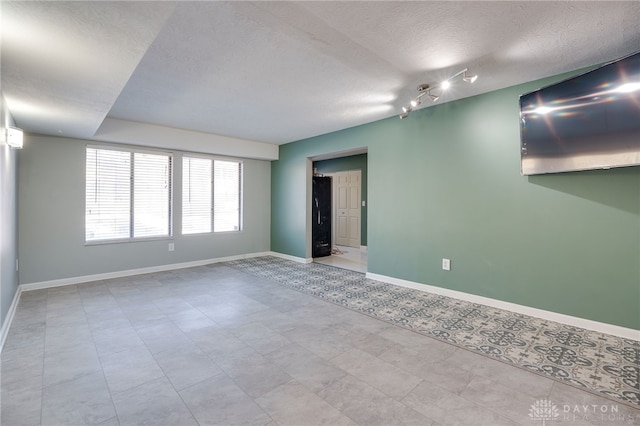 tiled empty room with rail lighting and a textured ceiling