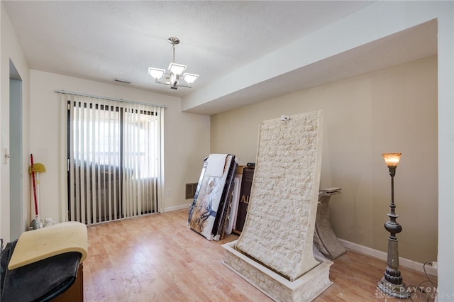 misc room featuring light hardwood / wood-style floors, a textured ceiling, and a notable chandelier