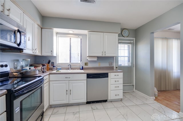 kitchen with sink, a healthy amount of sunlight, white cabinetry, and appliances with stainless steel finishes