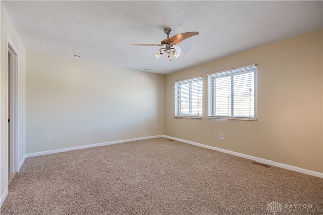 spare room featuring ceiling fan, carpet, and a textured ceiling