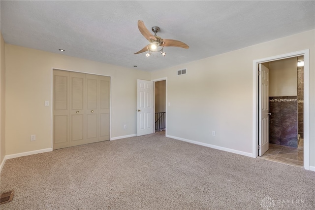 unfurnished bedroom featuring ceiling fan, light colored carpet, ensuite bathroom, and a closet