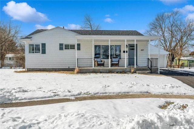 snow covered rear of property with covered porch