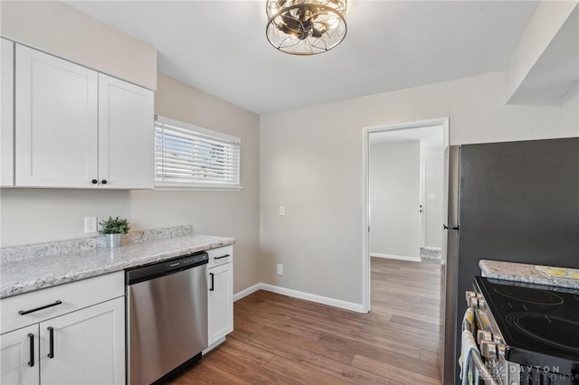 kitchen featuring white cabinetry, stainless steel appliances, light stone countertops, and hardwood / wood-style floors