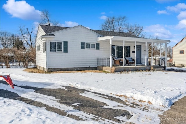 snow covered rear of property with a porch