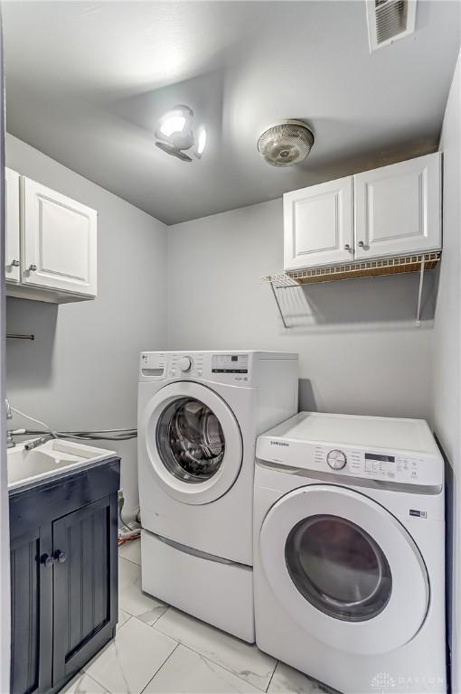 laundry room with cabinets, separate washer and dryer, and sink