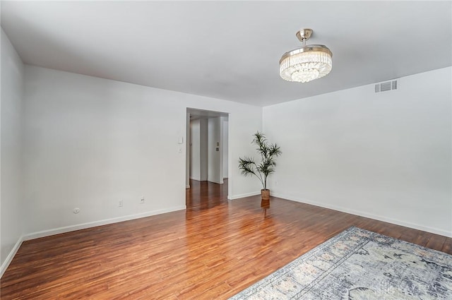 empty room featuring hardwood / wood-style flooring and a notable chandelier