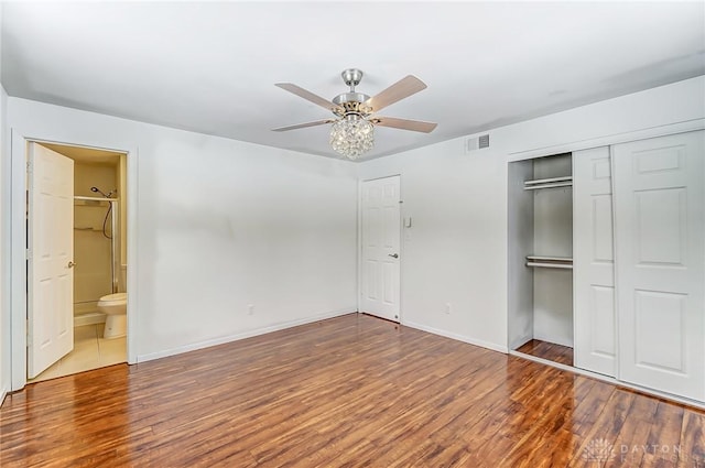 unfurnished bedroom with ceiling fan, hardwood / wood-style floors, a closet, and ensuite bath