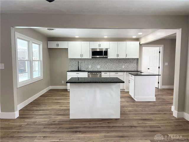 kitchen with a kitchen island, white cabinetry, stainless steel appliances, backsplash, and dark hardwood / wood-style floors