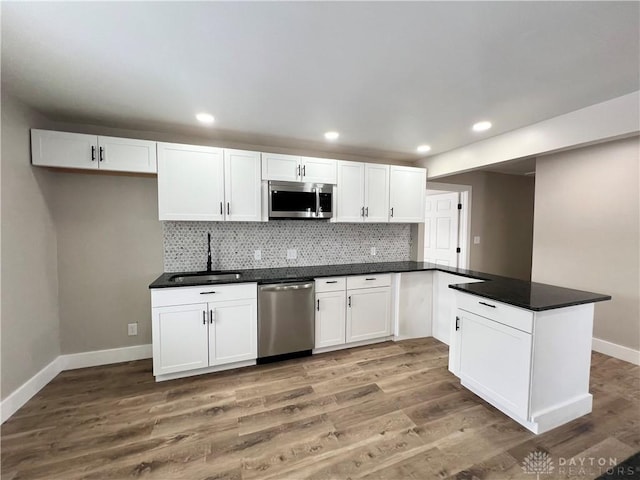 kitchen featuring hardwood / wood-style floors, white cabinets, appliances with stainless steel finishes, decorative backsplash, and sink