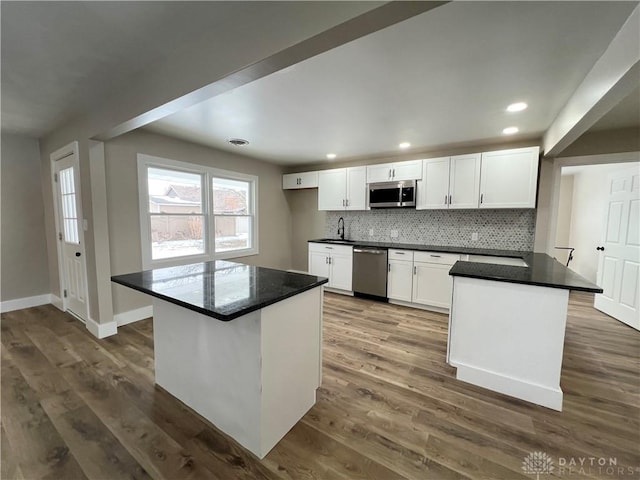 kitchen with tasteful backsplash, white cabinetry, a kitchen island, dark wood-type flooring, and stainless steel appliances