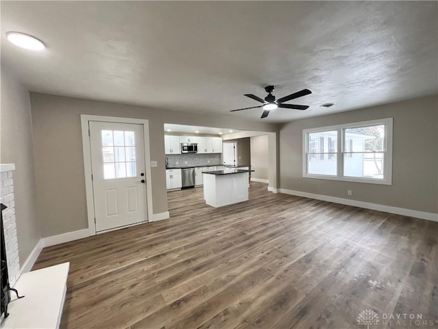 unfurnished living room with ceiling fan, dark hardwood / wood-style flooring, and a fireplace