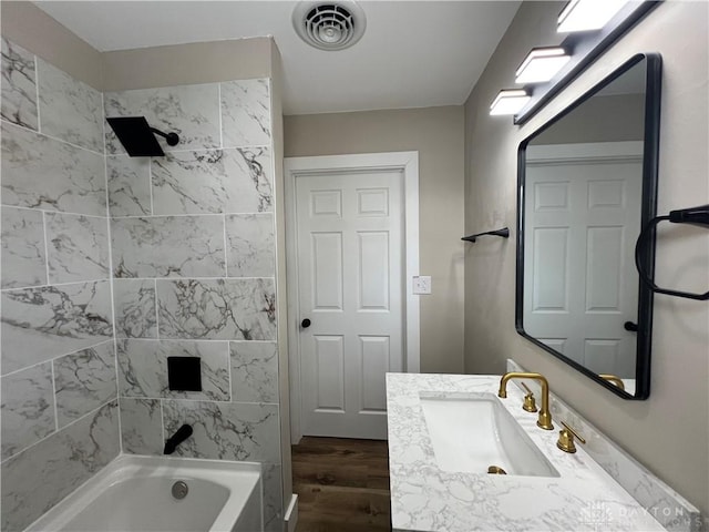 bathroom featuring tiled shower / bath and vanity