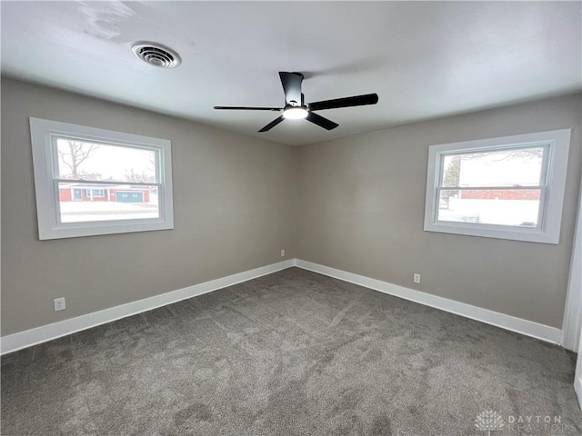 unfurnished room with ceiling fan, a healthy amount of sunlight, and dark carpet