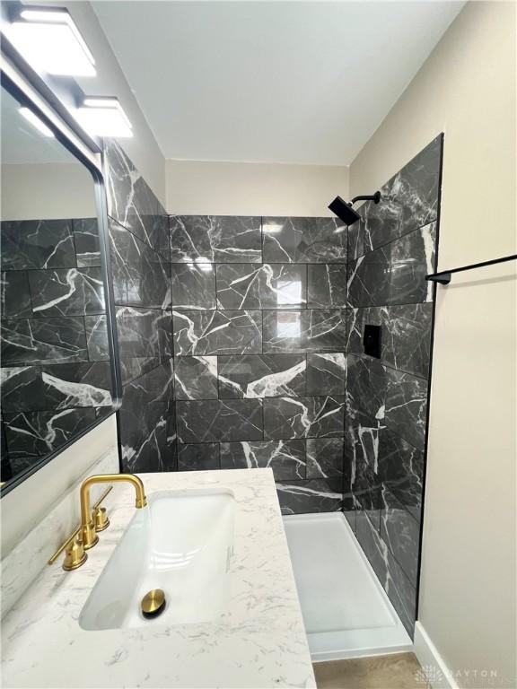 bathroom featuring tiled shower and vanity